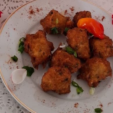 Assiette d'accras de morue dorés, parsemés de ciboulette et de piment